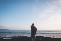 Visão traseira da mulher de pé em uma praia — Fotografia de Stock