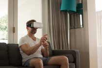 Чоловік використовує гарнітуру віртуальної реальності у вітальні вдома — стокове фото