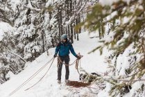 Hombre escalador sosteniendo la cuerda en la montaña nevada durante el invierno - foto de stock