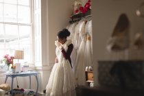 Afrikanerin wählt Hochzeitskleid aus Kleiderbügeln in Boutique — Stockfoto