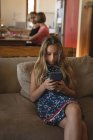 Дівчина використовує мобільний телефон у вітальні вдома — стокове фото