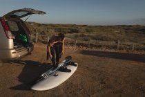 Surfista maschile con tavola da surf in spiaggia in una giornata di sole — Foto stock