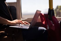 Mid section of businessman using laptop while travelling in bus — Stock Photo