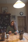 Жінка використовує мобільний телефон, маючи каву вдома — стокове фото