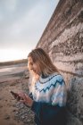 Jeune femme utilisant un téléphone portable sur une plage — Photo de stock