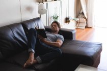 Homem lendo um livro na sala de estar em casa — Fotografia de Stock