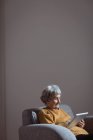 Femme âgée utilisant une tablette numérique dans le salon à la maison — Photo de stock
