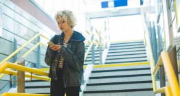 Молодая женщина с помощью мобильного телефона на лестнице — стоковое фото