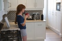 Mujer pensativa tomando café en la cocina en casa - foto de stock