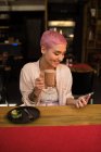 Stylish woman using mobile phone while having chocolate milkshake at restaurant — Stock Photo