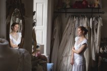 Giovane sposa in abito da sposa in piedi vicino alla finestra — Foto stock