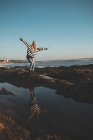 Женщина, стоящая с распростертыми руками на пляже в солнечный день — стоковое фото