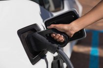 Close-up of woman charging electric car at charging station — Stock Photo