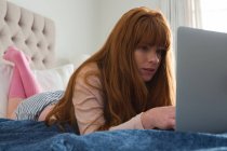 Frau mit roten Haaren benutzt Laptop im heimischen Schlafzimmer — Stockfoto