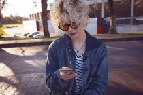 Молода жінка використовує мобільний телефон на міській вулиці — стокове фото
