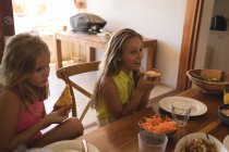 Братья и сёстры едят пиццу на кухне — стоковое фото