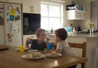 Geschwister frühstücken zu Hause am Esstisch — Stockfoto