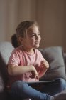 Маленькая девочка, использующая цифровой планшет в гостиной на дому — стоковое фото