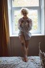 Женщина с цифровой планшет в спальне рядом с окном дома — стоковое фото