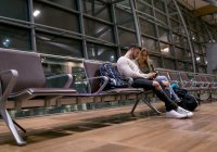 Пара с мобильным телефоном в зоне ожидания в аэропорту — стоковое фото