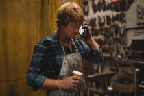 Blacksmith talking on the phone in workshop — Stock Photo