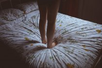 Женщина, стоящая на кровати в спальне дома — стоковое фото