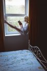 Donna che legge un libro vicino alla finestra di casa — Foto stock