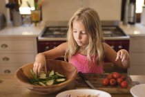 Mädchen bereitet zu Hause in der Küche Essen zu, kocht Salat mit Gurken und Tomaten — Stockfoto