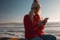 Young woman using mobile phone at beach — Stock Photo