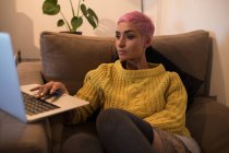 Стильна жінка використовує ноутбук у вітальні вдома — стокове фото