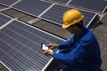 Чоловік-працівник використовує цифровий планшет на сонячній станції в сонячний день — стокове фото
