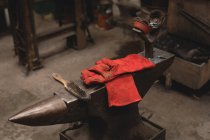 Cepillo de alambre de mano y guantes en yunque en taller - foto de stock