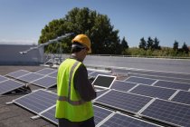 Male worker using laptop at solar station on a sunny day — Stock Photo