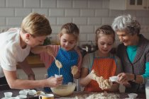 Семья из нескольких поколений готовит кекс на кухне дома — стоковое фото
