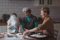 Familia multi-generación preparando magdalena en la cocina en casa - foto de stock