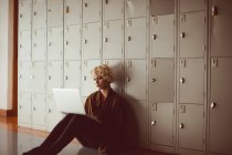 Young woman using laptop in locker room at library sitting on the floor — Stock Photo