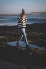 Giovane donna che cammina sulla roccia in spiaggia — Foto stock