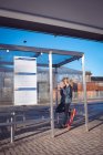 Жінка використовує мобільний телефон на автобусній зупинці в сонячний день — стокове фото