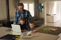 Pai e seus filhos usando laptop em casa — Fotografia de Stock