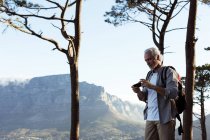 Seniorwanderer begutachtet Handy-Bild im Wald auf dem Land — Stockfoto