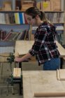 Carpinteiro feminino usando cinzel com martelo em um pedaço de madeira na oficina — Fotografia de Stock