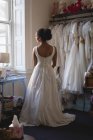 Donna di razza mista, sposa in abito bianco guardando attraverso la finestra a boutique — Foto stock
