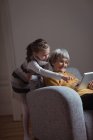 Abuela y nieta usando tableta digital en la sala de estar en casa - foto de stock