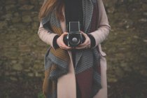 Seção média de mulher tirando foto com câmera vintage no campo — Fotografia de Stock