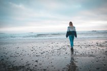 Вид сзади на женщину, идущую по пляжу — стоковое фото