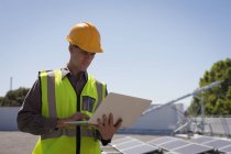 Male worker using laptop at solar station on a sunny day — Stock Photo