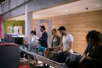 Commuters taking their baggage from baggage carousel at airport — Stock Photo