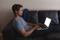 Человек, использующий ноутбук в гостиной дома — стоковое фото