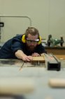 Плотник мужского пола проводит измерения древесины в мастерской — стоковое фото