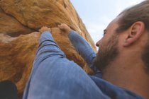 Randonneur masculin escalade montagne rocheuse à la campagne par une journée ensoleillée — Photo de stock
